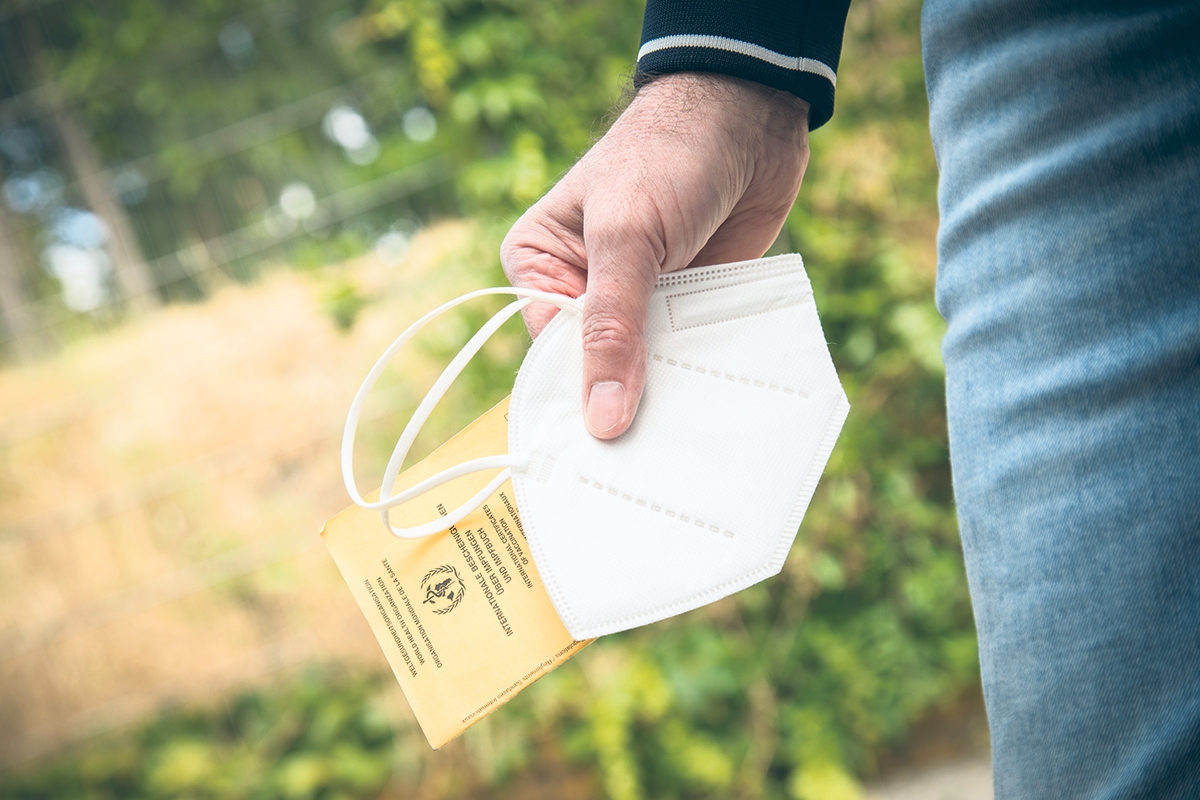 Person hält eine FFP-2 Maske und einen Impfpass in der Hand