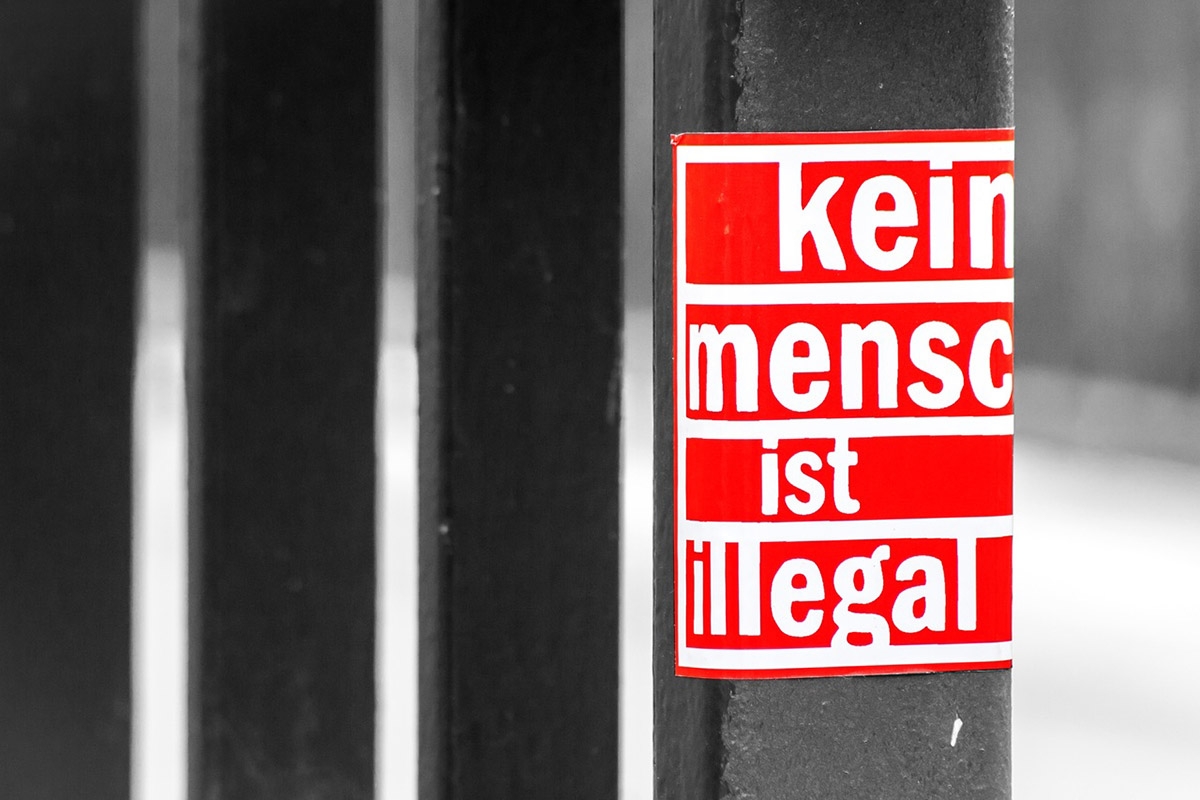 Roter Aufkleber auf Gitter "Kein Mensch ist illegal"