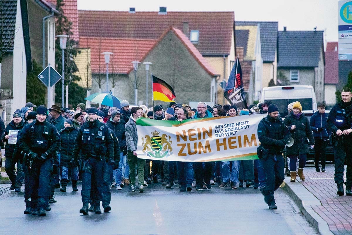 Demonstrierende mit Plakat "Nein zum Heim"