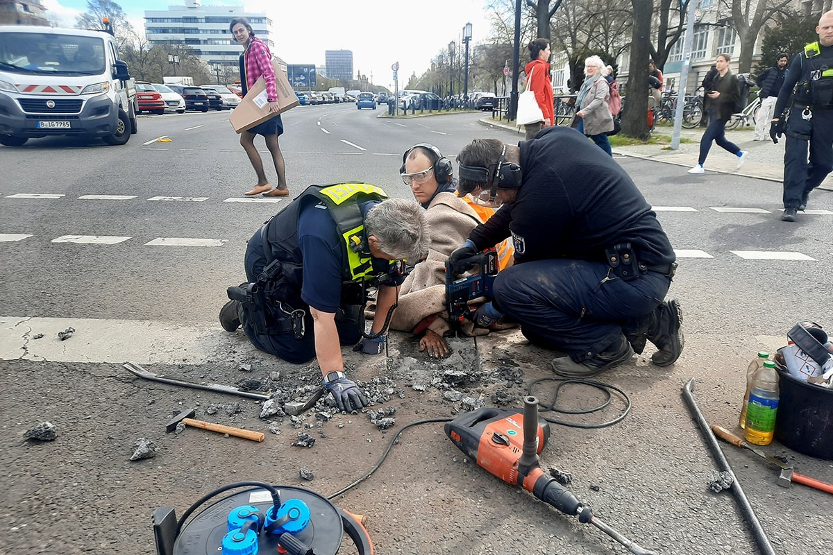 Polizisten lösen die Hand eines Aktivisten der Letzten Generation