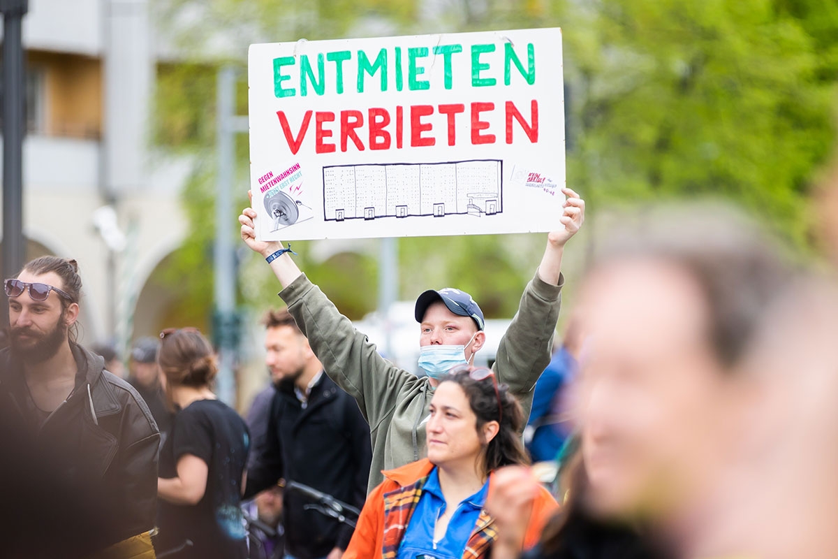 Protestierender mit einem Schild, auf dem eine Zeichnung des von der Räumung bedrohten Gebäudes in der Habersaathstraße zu sehen ist,