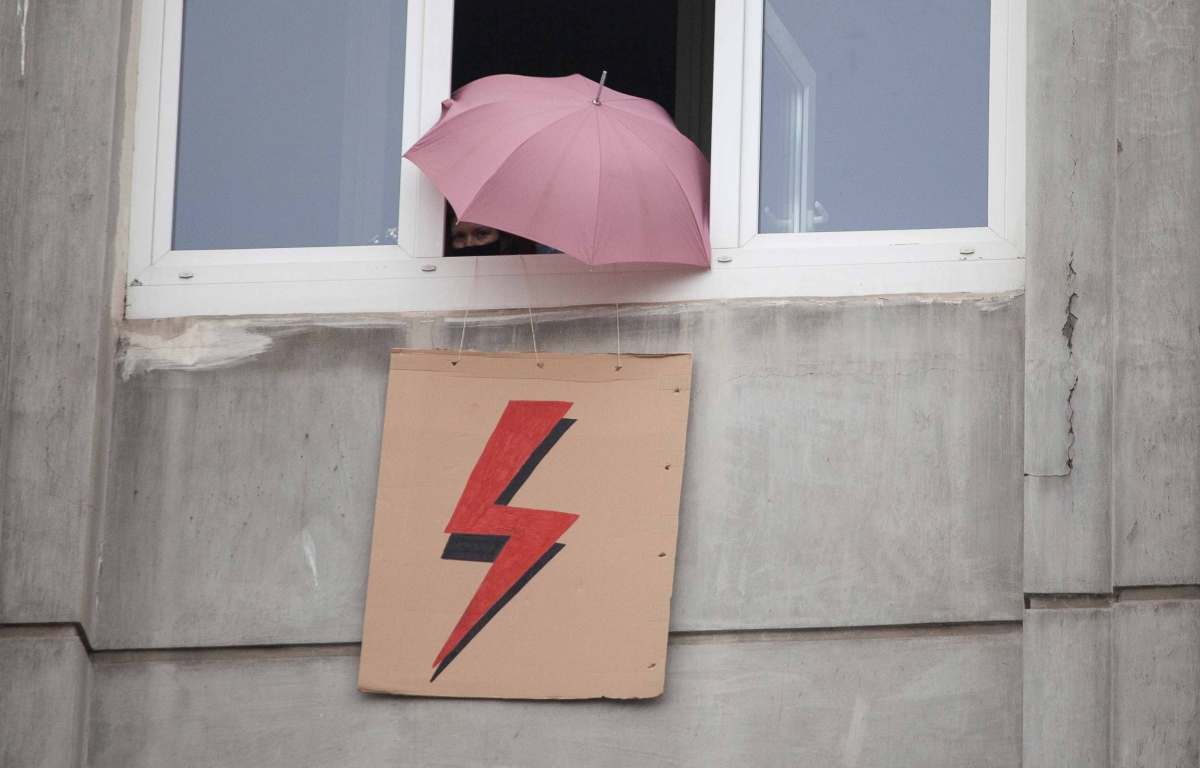 Geöffnetes Fenster aus dem ein Schild mit Blitz und ein Regenschirm ragen