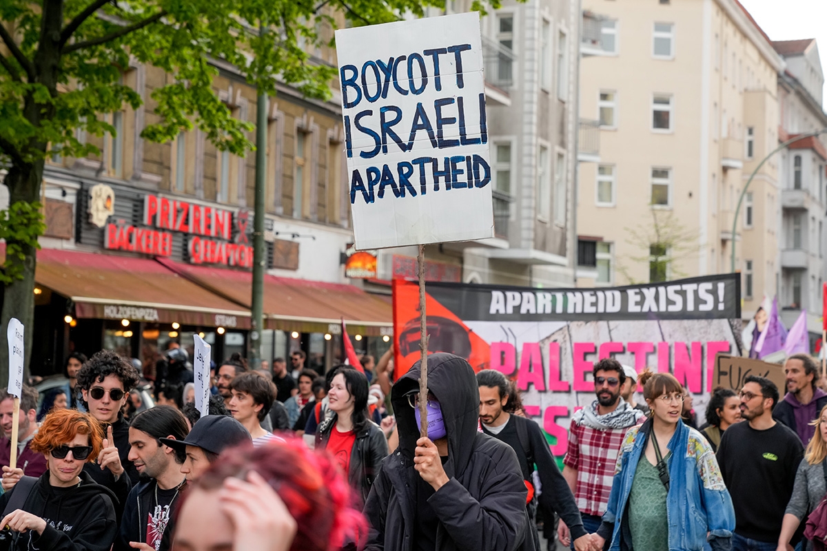 Demonstrant bei der Revolutionären 1.-Mai-Demonstration in Berlin mit Schild "Boycott Israeli Apartheid"eder israelfeindliche Schilder am Start