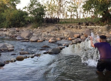 Mann steht im Wasser auf der anderen Seite des Flusses befinden sich mehrere Soldaten