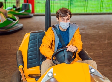 Person mit Maske im Autoscooter