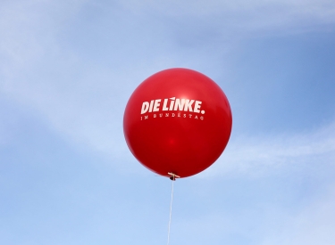 Roter Luftballon "Die Linke" am Himmel