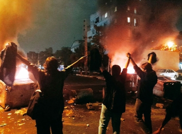 Protest in Teheran, Frauen ohne Kopftuch im Hintergrund Feuer