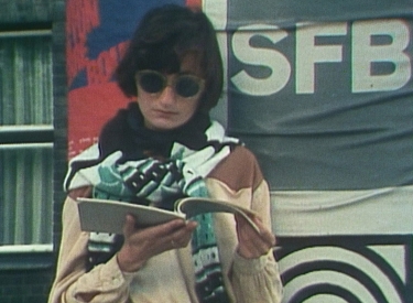 Elfriede Jelinek mit Sonnenbrille liest in einem Heft