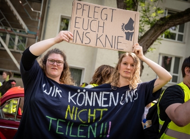 Zwei Demostrierende tragen ein großes T-Shirt mit der Aufschrift "Wir können uns nicht teilen!"