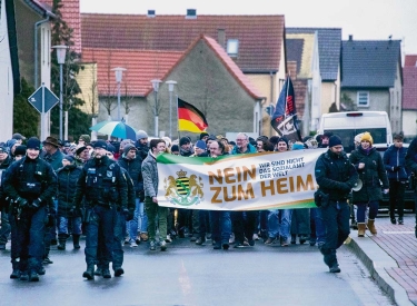 Demonstrierende mit Plakat "Nein zum Heim"