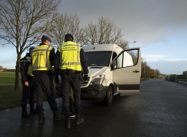 Zwei Männer in gelben Sicherheitswesten kontrollieren einen Kleintransporter