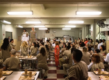 Blanca Flores (Laura Gómez) und Piper Chapman (Taylor Schilling, r.) haben sich aus Protest auf einen Tisch der Mensa gestellt