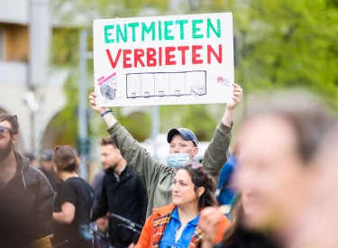 Protestierender mit einem Schild, auf dem eine Zeichnung des von der Räumung bedrohten Gebäudes in der Habersaathstraße zu sehen ist,