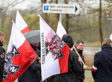 Gruppe von etwa 15 Personen mit Fahnen und Armbinden mit Symbolen der Narodowe Siły Zbrojne, NSZ